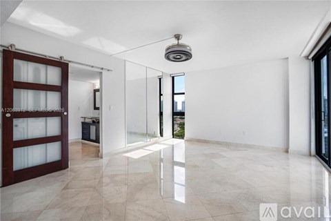 A spacious, well-lit room with marble flooring and a large window.