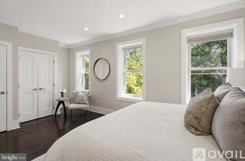 A bedroom with a large bed and a window with a view of trees.