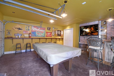 A bedroom with a bed, two chairs, and a TV.