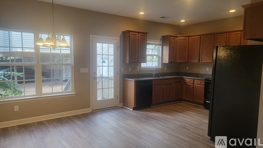 A kitchen with wooden floors and a black refrigerator.
