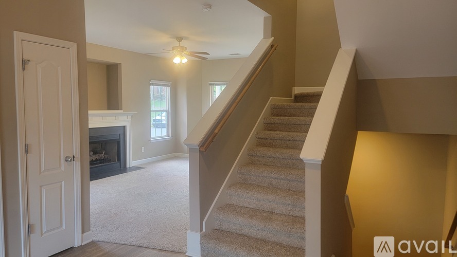 A staircase with a beige carpeted runner and white risers leads to a second floor.