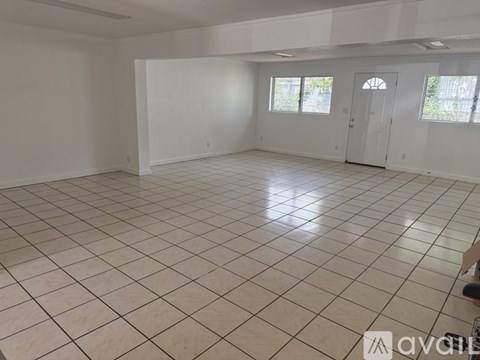 A spacious room with white walls and a tiled floor.