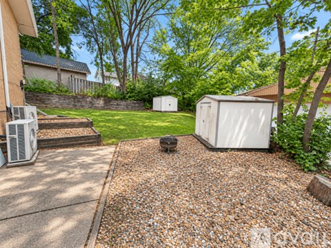 A backyard with a shed, a gravel area, and a concrete walkway.
