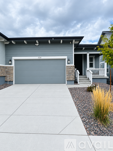 A house with a grey garage door and a white porch.