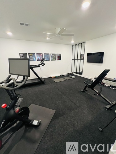 A gym room with a stationary bike, a treadmill, and a bench.