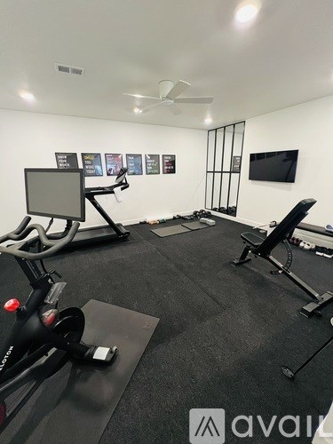 A gym room with a stationary bike, a treadmill, and a bench.