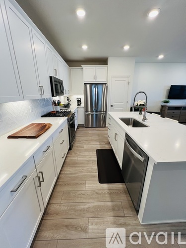 A modern kitchen with white cabinets and a wooden cutting board.