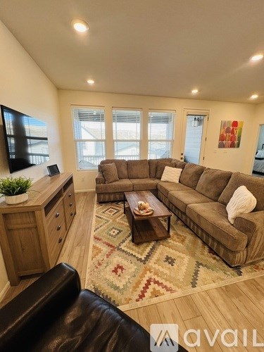 A living room with a brown couch and a rug.