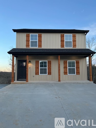A two-story house with a black door and windows with brown trim.