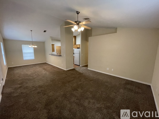A spacious room with a ceiling fan and carpeted floor.