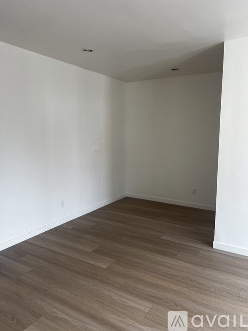 A room with wooden flooring and white walls.