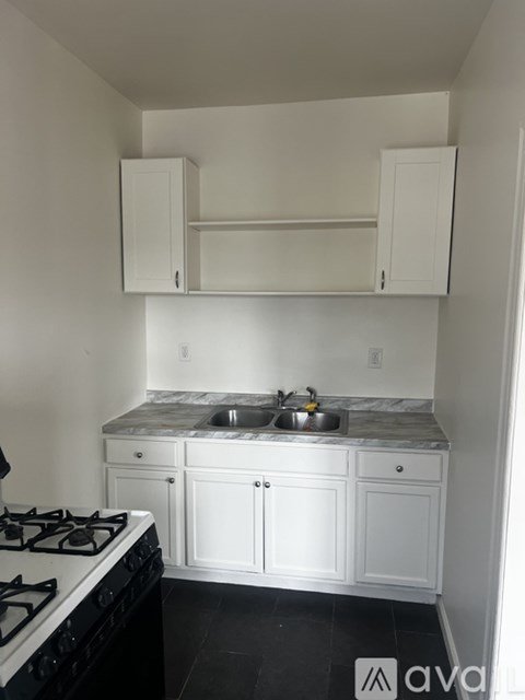 A kitchen with white cabinets and a black stove top.