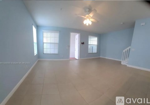 A spacious room with a ceiling fan and a door leading to another room.