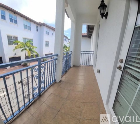 A balcony with a metal railing and a view of a building and trees.