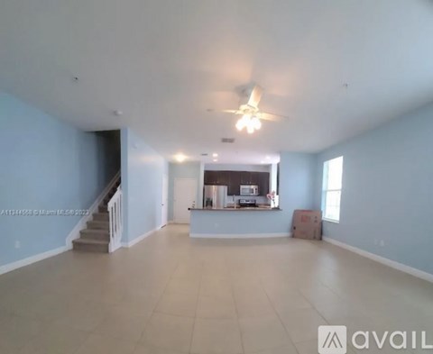 A spacious living room with a staircase on the left and a box on the right.