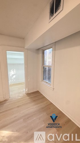 A room with wooden flooring and a window with a view of a building outside.