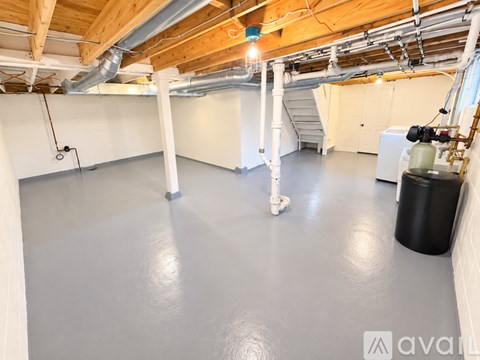 A spacious room with a concrete floor and a staircase in the background.