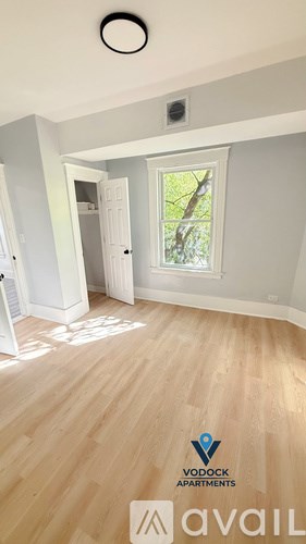 A room with wooden flooring and a window with a view of trees.