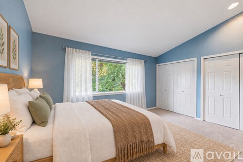 A bedroom with blue walls and a large bed with a brown blanket.