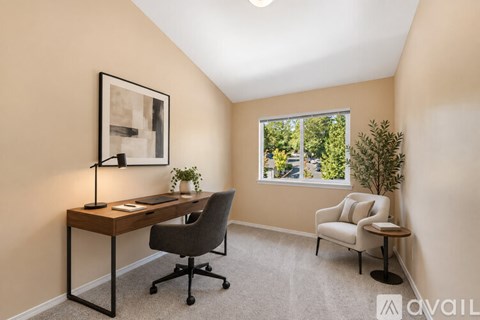 A room with a desk, chair, and a window with a view of trees.