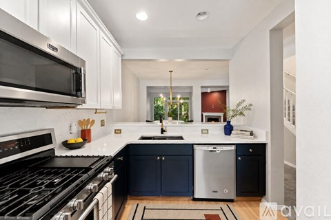 A modern kitchen with dark blue cabinets and stainless steel appliances.