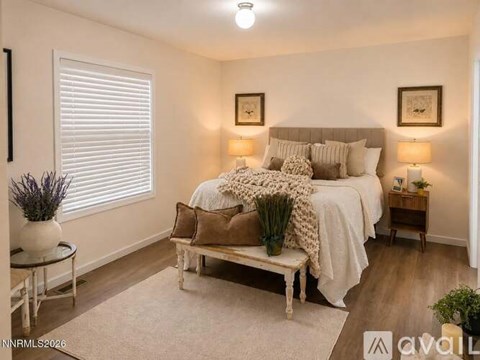 A bedroom with a bed, bench, and two lamps.