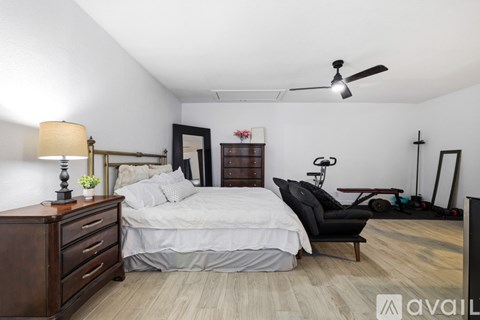 A bedroom with a bed, a chair, and a ceiling fan.