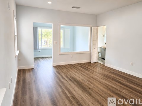 A spacious room with wooden flooring and a large window.