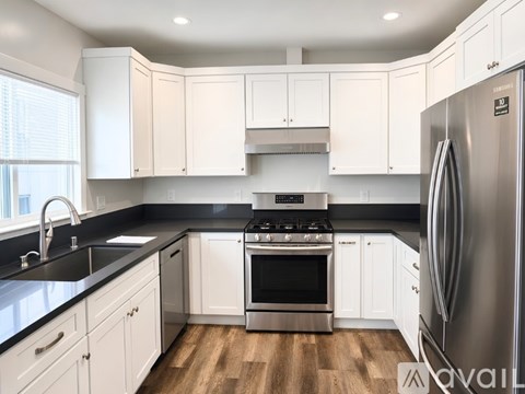 A kitchen with white cabinets and a black countertop.