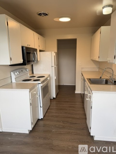 A kitchen with white appliances and cabinets.