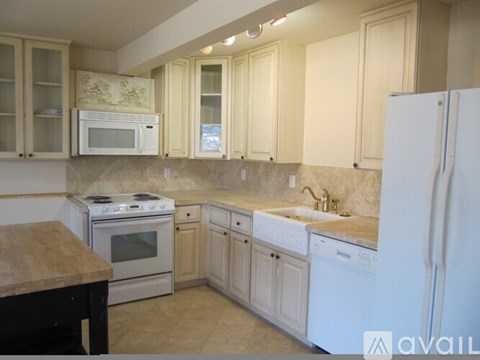 A kitchen with white appliances and wooden cabinets.