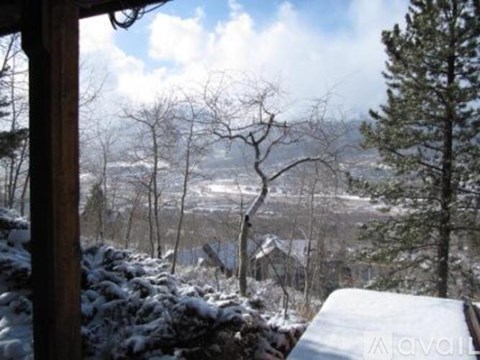 A snowy landscape with trees and a wooden structure in the foreground.