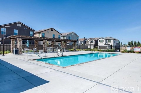 A swimming pool surrounded by a fence and a few houses in the background.
