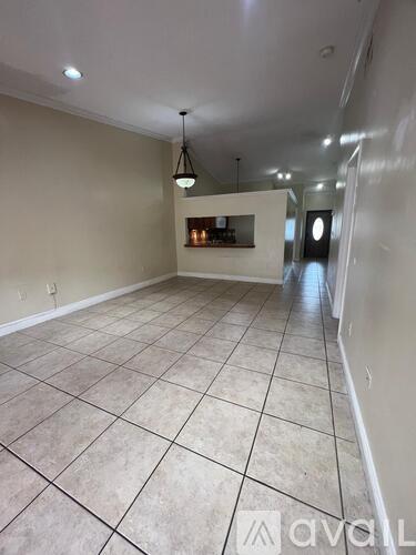 A spacious room with tiled flooring and a bar area in the corner.