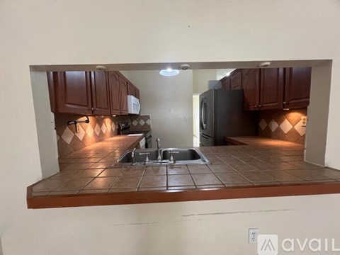 A kitchen with brown cabinets and a black refrigerator.