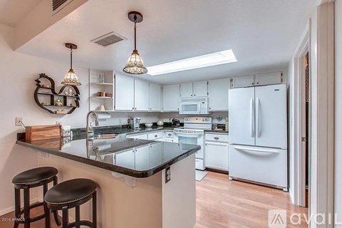 A kitchen with white appliances and a black counter top.