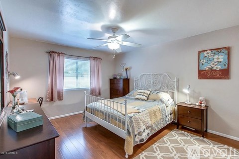 A bedroom with a bed, nightstand, and a ceiling fan.