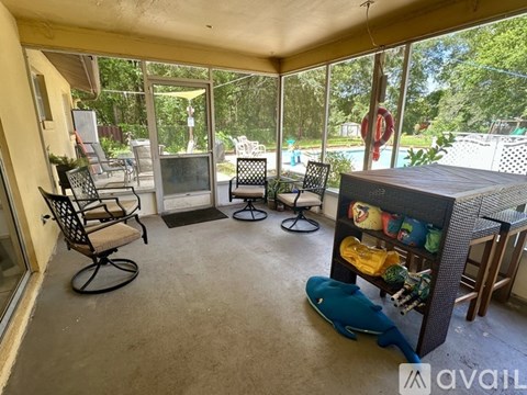 A sunroom with a pool and patio furniture.