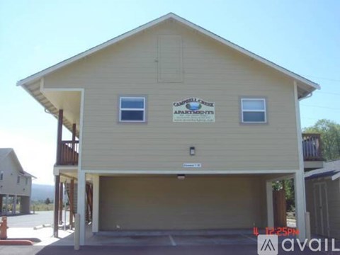 A two-story building with a garage and a sign that says "Campbell Apartments".
