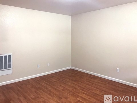 A room with wooden flooring and a window with blinds.