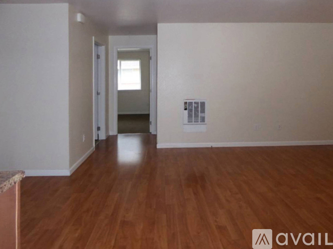 A room with wooden floors and a doorway leading to another room.