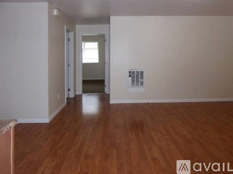 A room with wooden floors and a doorway leading to another room.