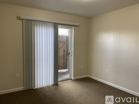 A room with a carpeted floor and a sliding glass door leading to a balcony.