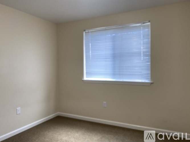 A room with a window covered by white blinds.