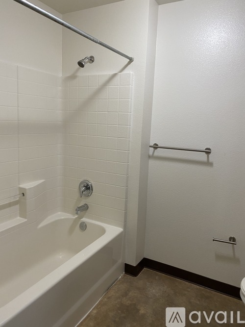 A white tiled bathroom with a bathtub and a towel bar.