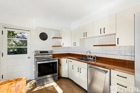 A kitchen with white cabinets and a wooden counter top.