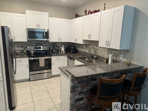 A kitchen with white cabinets and a granite countertop.