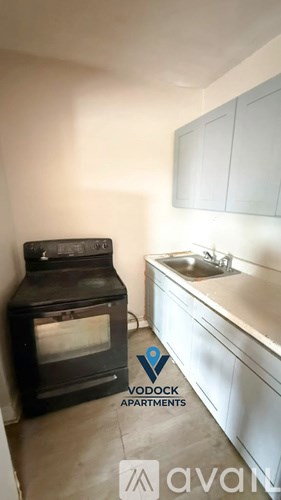 A wood stove is in a kitchen with white cabinets.