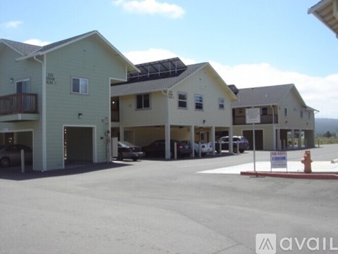 A parking lot with a few cars and a building with a sign that says "AVAILABLE".