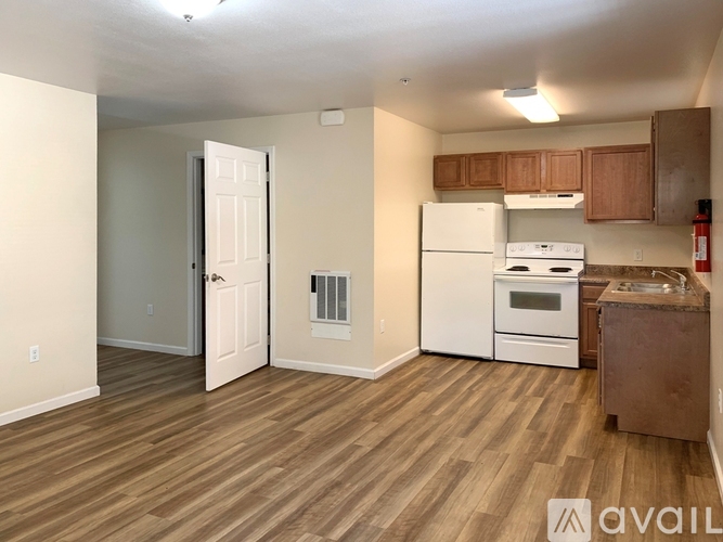A kitchen with white appliances and wooden floors.